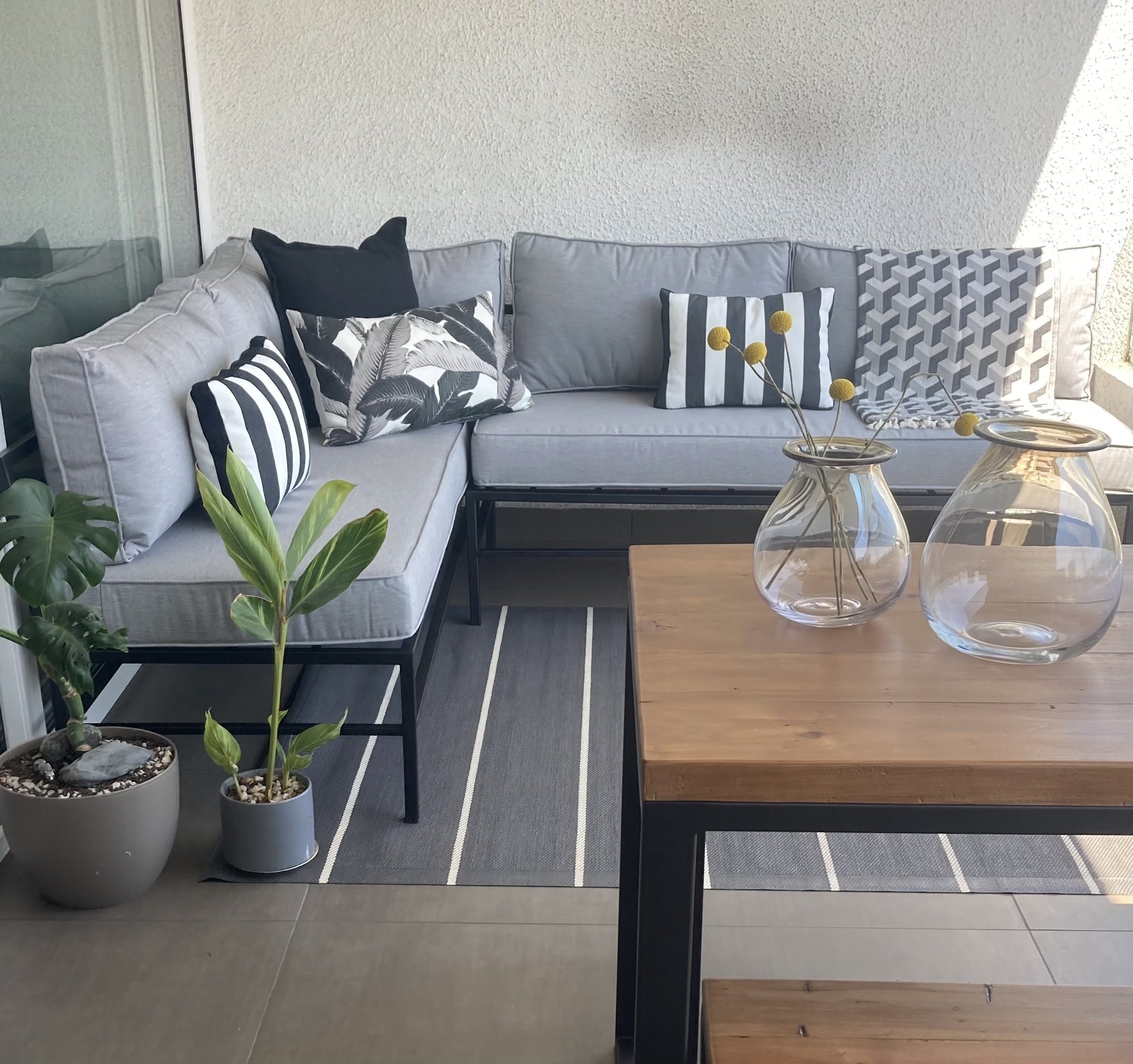 terraza_linda_de_sofa_de_fierro_con_cojines_grises_y_mesa_de_madera_y_fierro.jpg