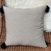 Cojines en tonos amarillos y beige - cojin decorativo cuadrado beige con pompones negros en las esquinas.JPG