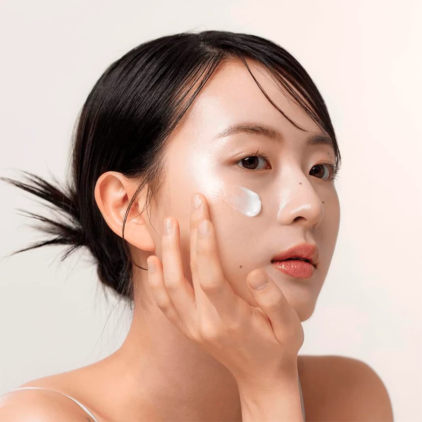 Modelo aplicando Dynasty Cream Beauty of Joseon en la mejilla. La crema anti-aging coreana se absorbe rápidamente aportando hidratación 24h y efecto glass skin luminoso. Apta para todo tipo de piel.
