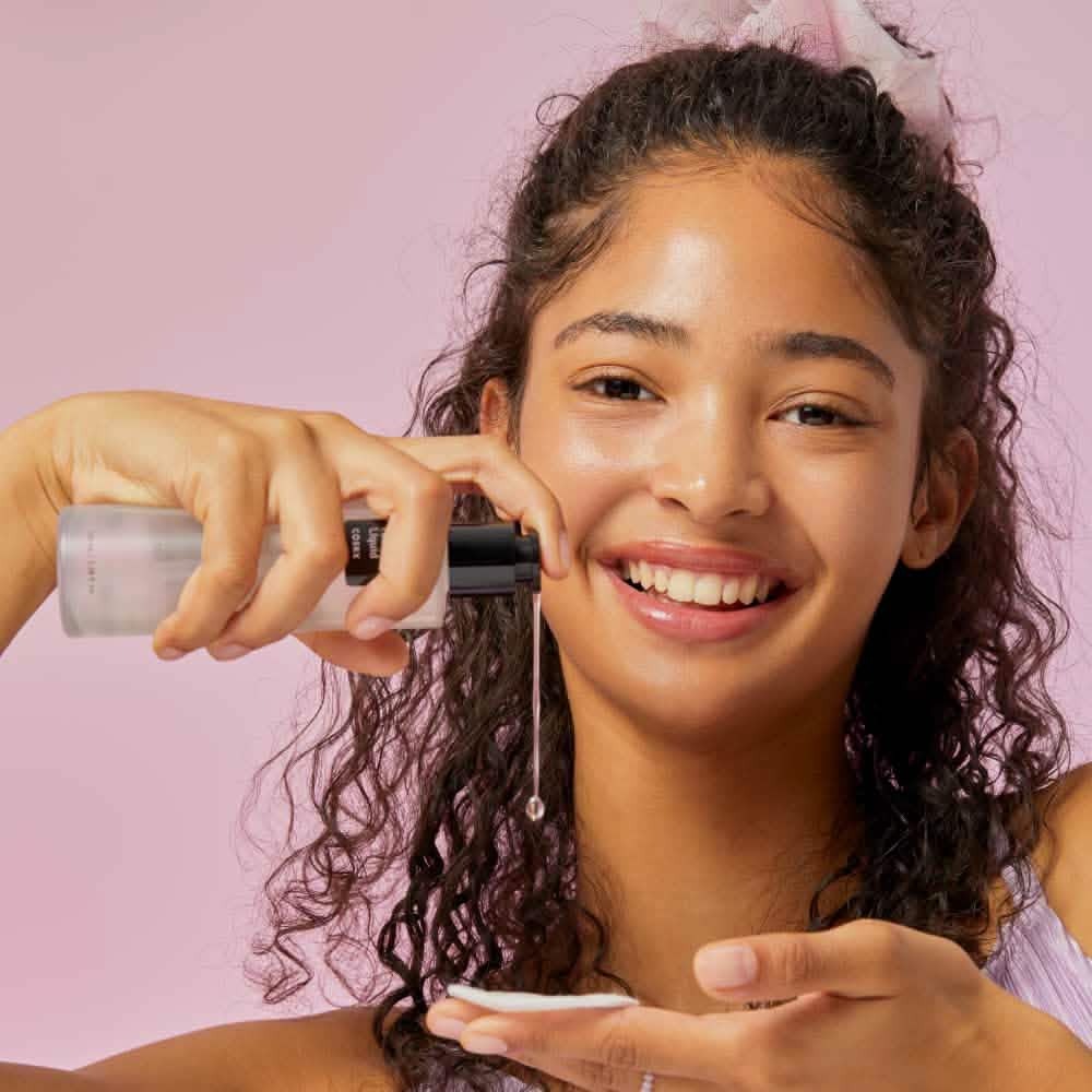Mujer con el CosRx BHA Blackhead Power Liquid 100ml. Exfoliante BHA K-Beauty con 67.8% Salix Alba Water y Betaine Salicylate — sin fragancia, sin alcohol, sin parabenos. Disponible en Kosmetica.cl.