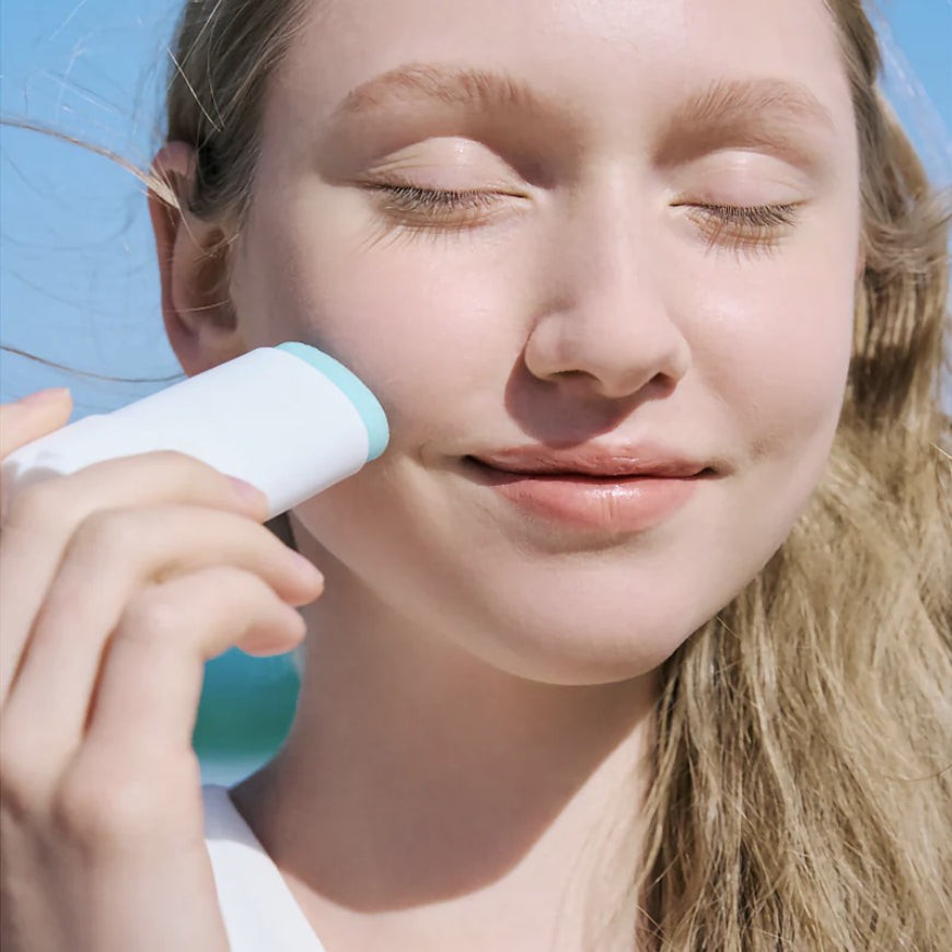 Modelo aplicando el protector solar en barra SKIN1004 Hyalu-Cica Silky Fit Sun Stick sobre la mejilla.