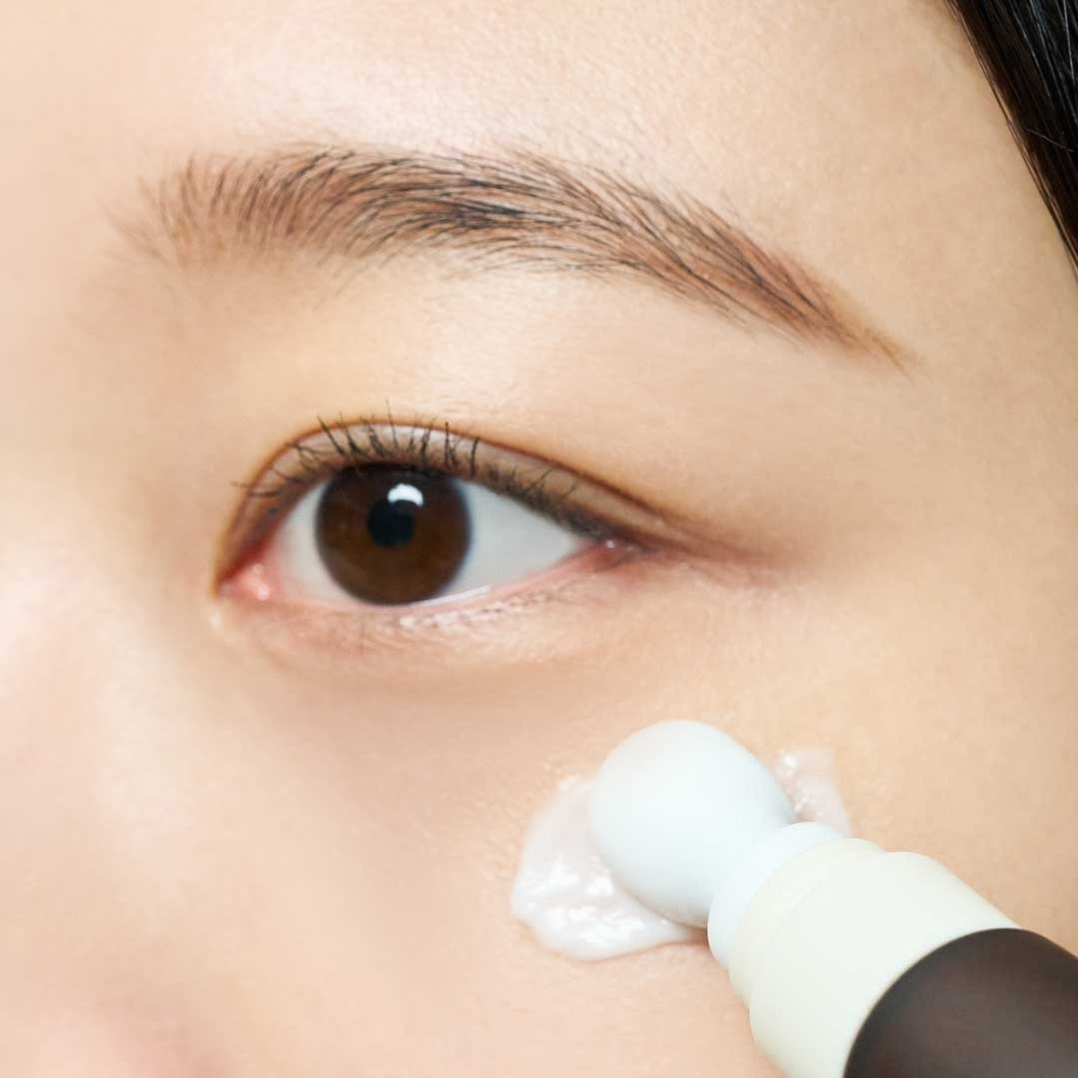 Primer plano de la aplicación de SKIN1004 Probio-Cica Bakuchiol Eye Cream en el contorno de ojos.