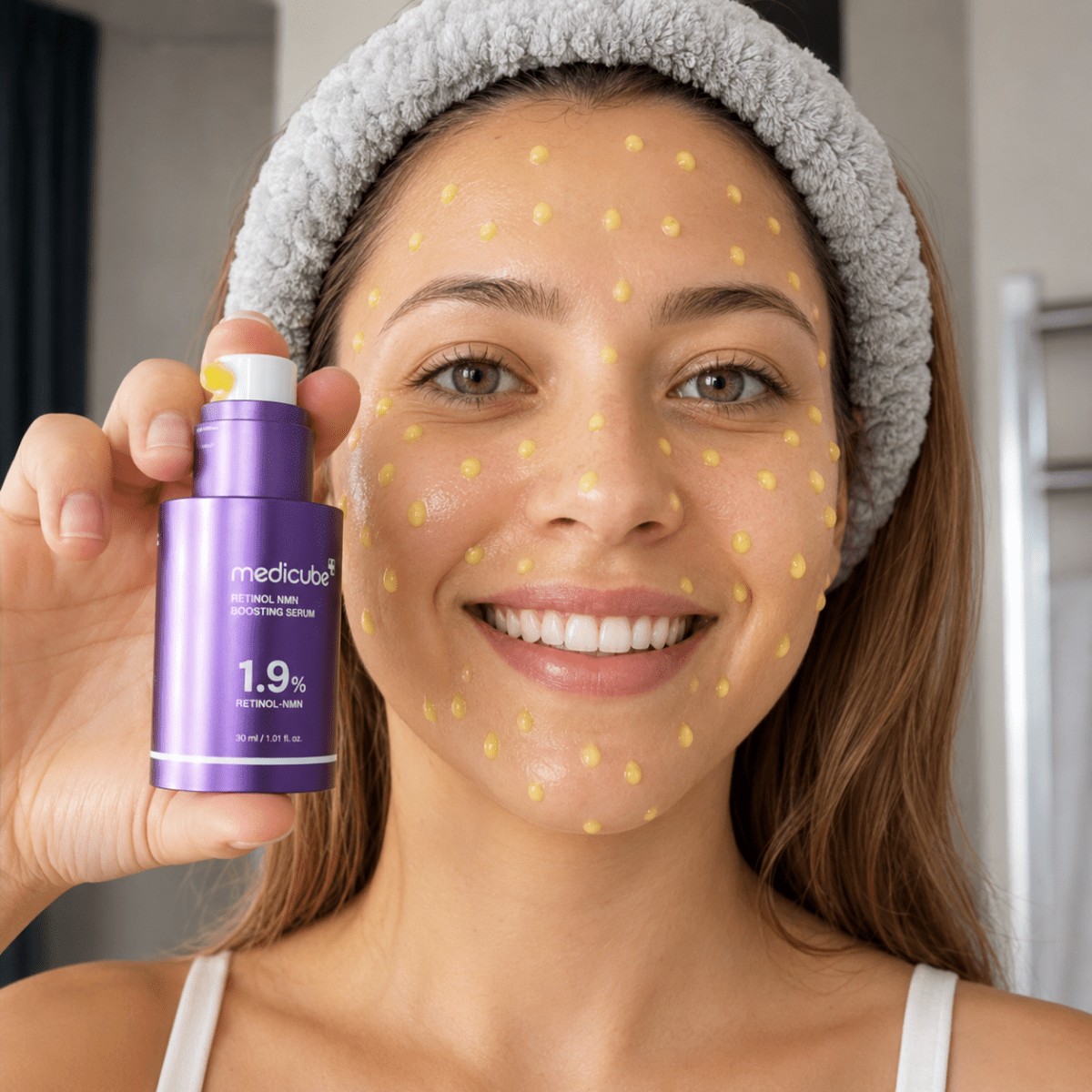 Modelo sonriente sostiene el frasco de Medicube Retinol Boosting Serum.