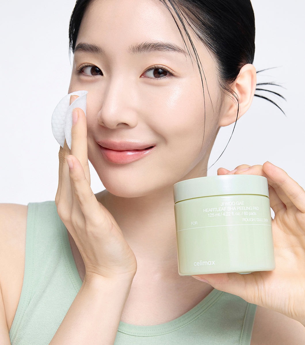 Modelo usando un pad de Celimax JIWOOGAE Heartleaf BHA Peeling Pad en el rostro.