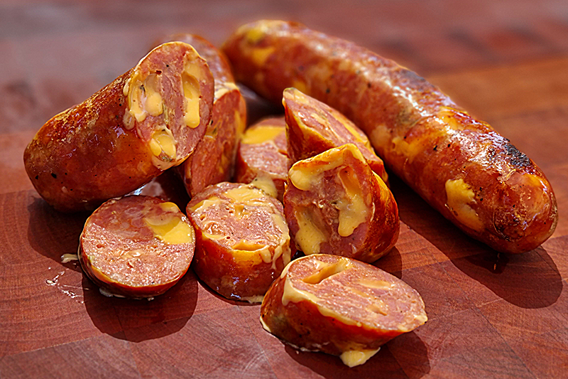 Longanizas de cerdo con trozos de jalapeño y cheddar cortadas sobre una tabla