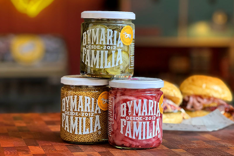 Frascos de vidrio con mostaza, pepinos y cebolla encurtida artesanales.