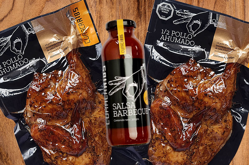Medios pollos ahumados envasados al vacío junto a una botella de salsa barbecue artesanal